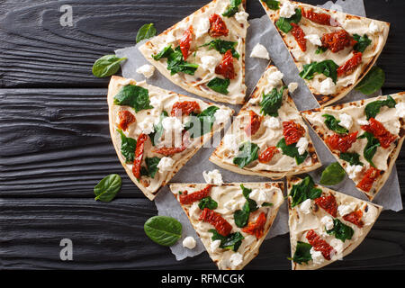 Pains plats d'hummus, tomates séchées, épinards et fromage de chèvre sur la table. Haut horizontale Vue de dessus Banque D'Images