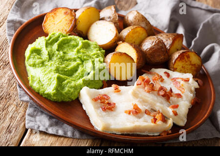La morue norvégienne lutefisk servi avec purée de pois, de pommes de terre et bacon close-up sur une plaque horizontale. Banque D'Images
