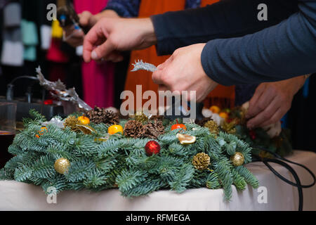 Couronne de Noël Atelier de tissage. Femme de couronnes de décoration mains faites de branches d'épinette, cônes et diverses décorations organique sur la table Banque D'Images