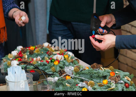 Couronne de Noël Atelier de tissage. Femme de couronnes de décoration mains faites de branches d'épinette, cônes et diverses décorations organique sur la table Banque D'Images