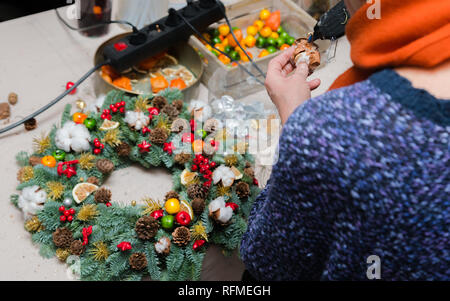 Couronne de Noël Atelier de tissage. Femme de couronnes de décoration mains faites de branches d'épinette, cônes et diverses décorations organique sur la table Banque D'Images