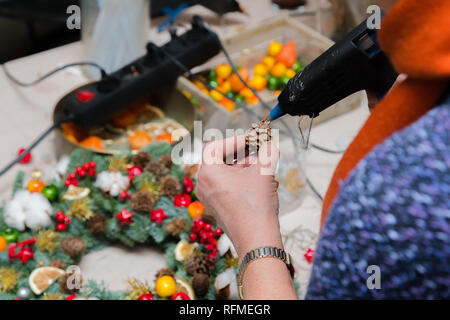 Couronne de Noël Atelier de tissage. Femme de couronnes de décoration mains faites de branches d'épinette, cônes et diverses décorations organique sur la table Banque D'Images