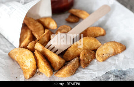 Les quartiers de pommes de terre avec sauce tomate de fourche en bois Banque D'Images