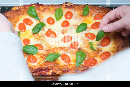 Woman decorating lasagnes végétariennes aux herbes dans la plaque de cuisson qui vient d'être pris hors du four Banque D'Images