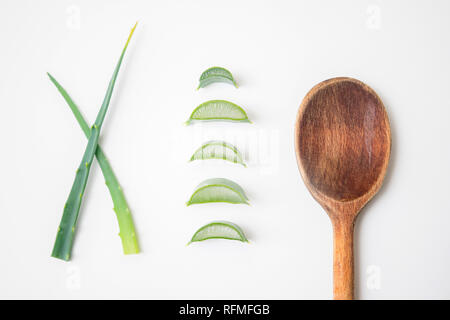 L'aloe vera de brindilles et de tranches de plantes sur fond blanc avec une cuillère en bois sur le côté Banque D'Images