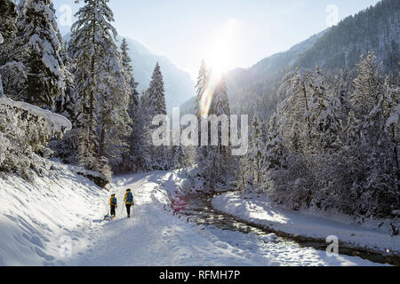 En plein air d'hiver conte de bouilloire pour les enfants ou même des adultes, la mère et le fils marche sur piste couverte de neige tirant des traîneaux, Slovénie, Krnica valley Banque D'Images