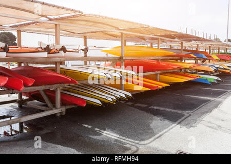 Dans la lumière du soleil, rouge, jaune et blanc des kayaks mis à l'envers sur metal racks de stockage. Stocké dans le canot Brest, France 28 mai 2018. Banque D'Images