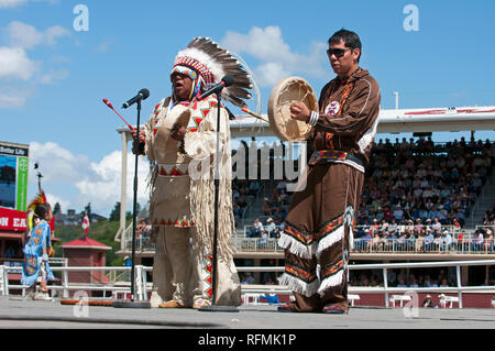 Canadian native en vêtements traditionnels chantant et jouant le tambour typique au Stampede de Calgary, Calgary, Alberta, Canada Banque D'Images