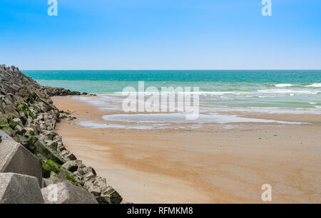 Vue sur la mer au cours de l'écoulement, sable, brise-lames avec des blocs de béton et de ciel bleu.mer du Nord en France. Banque D'Images