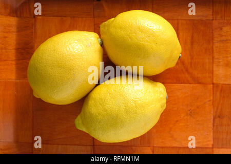 Nature morte avec trois citrons jaunes mûrs sur bac en bois brun gros plan Vue de dessus Banque D'Images