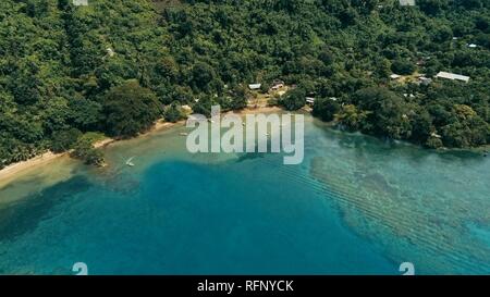 Drone aérien image d'un village du pacifique sud sur une île avec une magnifique barrière de corail et la forêt tropicale luxuriante jungle tandis que un petit moteur b Banque D'Images