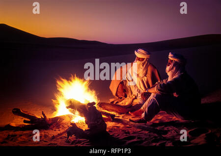 Le Tassili N'Ajjer, ALGÉRIE - 10 janvier 2002 : des inconnus au coucher du soleil avec le feu dans les dunes de sable du désert du Sahara algérien, de l'Afrique, le Tassili N'Ajjer Banque D'Images