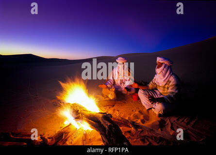Le Tassili N'Ajjer, ALGÉRIE - 10 janvier 2002 : des inconnus au coucher du soleil avec le feu dans les dunes de sable du désert du Sahara algérien, de l'Afrique, le Tassili N'Ajjer Banque D'Images