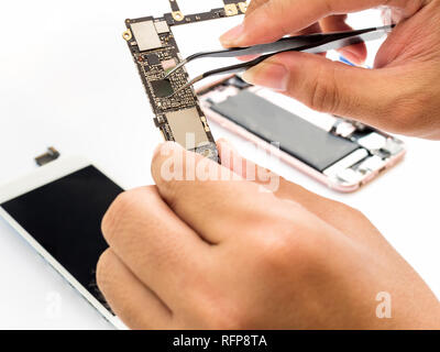 Close-up de serrage à main technicien sur smartphone processeur sur la carte logique floue fond composant smartphone Banque D'Images