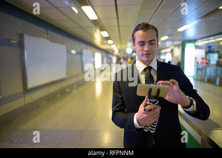 Young businessman vlogging avec phone at train station Banque D'Images