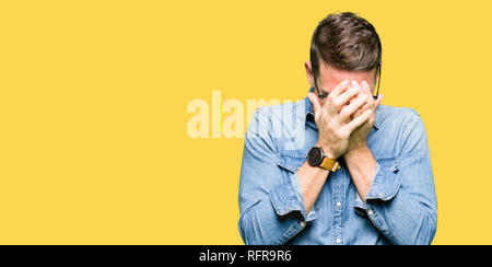 Bel homme portant des lunettes avec expression triste couvrant le visage avec les mains en pleurant. Concept de dépression. Banque D'Images