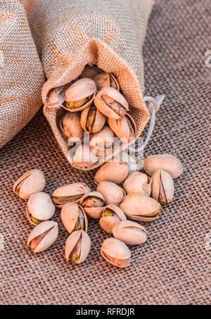 Sac de pistaches (Pistacia vera) renversé sur surface sac Banque D'Images