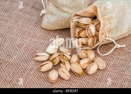 Sac de pistaches (Pistacia vera) renversé sur surface sac Banque D'Images