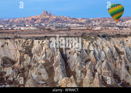 Montgolfière sur les formations rocheuses de la Cappadoce avec la ville en arrière-plan d'Uchisar, Turquie Banque D'Images