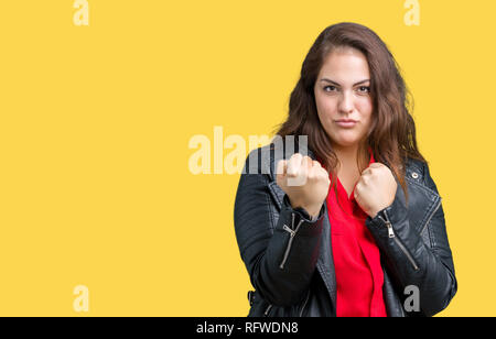 Taille plus belle jeune femme portant une veste en cuir de mode sur fond isolé prêt à combattre avec fist, geste de défense en colère et contrarié fa Banque D'Images