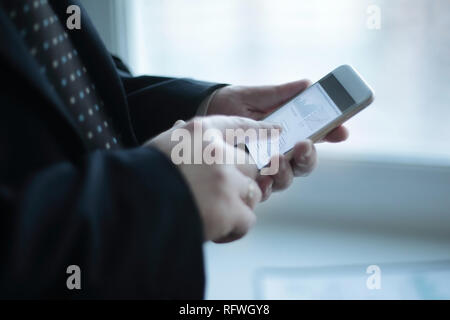 Close up. Un homme d'affaires utilise un smartphone pendant près d'une table de travail dans le bureau Banque D'Images