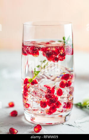 Boissons de fête, gin tonic cocktail de grenade ou de l'eau avec de la glace. detox Focus sélectif, l'espace de copie de texte, de la surface de la table en béton gris clair. Banque D'Images