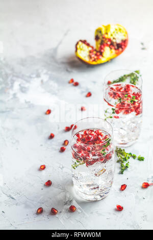 Boissons de fête, gin tonic cocktail de grenade ou de l'eau avec de la glace. detox Focus sélectif, l'espace de copie de texte, de la surface de la table en béton gris clair. Banque D'Images