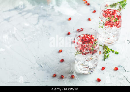 Boissons de fête, gin tonic cocktail de grenade ou de l'eau avec de la glace. detox Focus sélectif, l'espace de copie de texte, de la surface de la table en béton gris clair. Banque D'Images