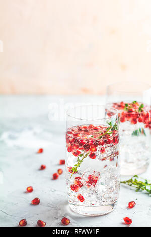 Boissons de fête, gin tonic cocktail de grenade ou de l'eau avec de la glace. detox Focus sélectif, l'espace de copie de texte, de la surface de la table en béton gris clair. Banque D'Images