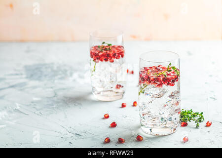 Boissons de fête, gin tonic cocktail de grenade ou de l'eau avec de la glace. detox Focus sélectif, l'espace de copie de texte, de la surface de la table en béton gris clair. Banque D'Images