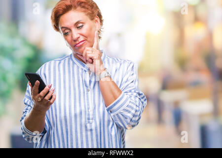 Atrractive young redhead woman texting en utilisant blackberry sur fond isolé visage sérieux de penser à question, idée très confus Banque D'Images