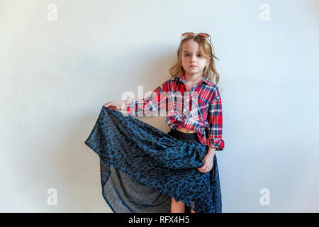 Sweet happy fashion adorable petite fille habillée comme hippie hippie gypsy cowboy dans lunettes standing against white wall background à la lumière Banque D'Images