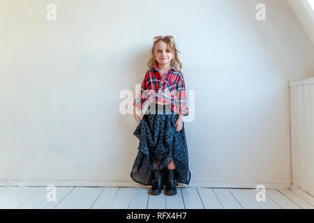 Sweet happy fashion adorable petite fille habillée comme hippie hippie gypsy cowboy dans lunettes standing against white wall background à la lumière Banque D'Images