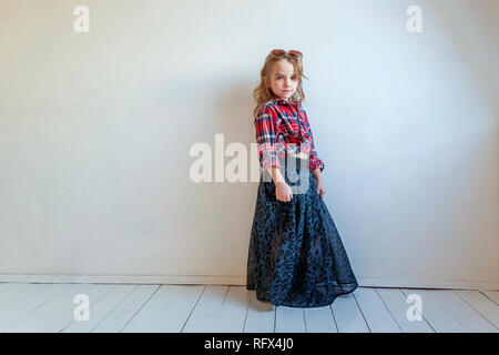 Sweet happy fashion adorable petite fille habillée comme hippie hippie gypsy cowboy dans lunettes standing against white wall background à la lumière Banque D'Images