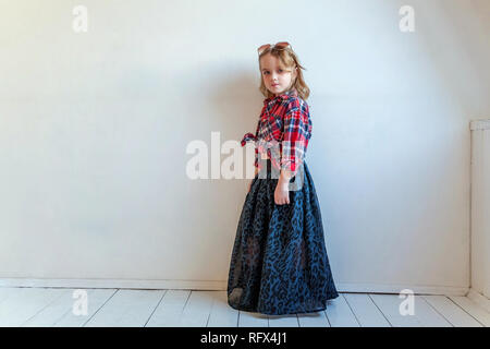 Sweet happy fashion adorable petite fille habillée comme hippie hippie gypsy cowboy dans lunettes standing against white wall background à la lumière Banque D'Images