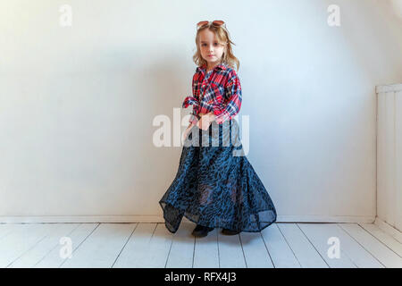 Sweet happy fashion adorable petite fille habillée comme hippie hippie gypsy cowboy dans lunettes standing against white wall background à la lumière Banque D'Images