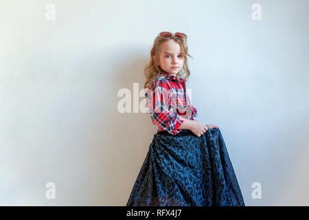 Sweet happy fashion adorable petite fille habillée comme hippie hippie gypsy cowboy dans lunettes standing against white wall background à la lumière Banque D'Images