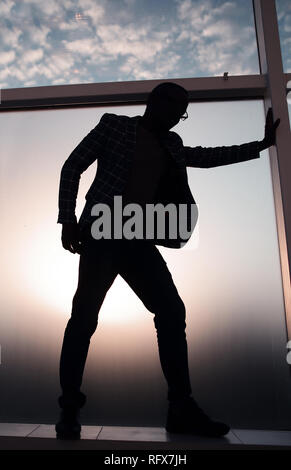 Silhouette d'un homme debout près de la fenêtre du bureau Banque D'Images