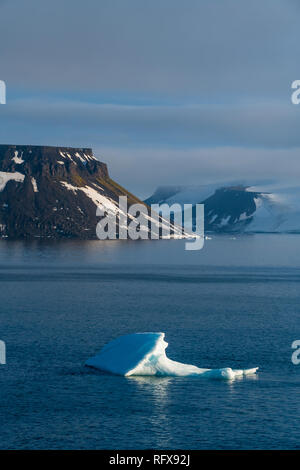 Iceberg flottant dans l'avant du tableau plat montagnes couvertes de glace, l'archipel François-Joseph, Oblast d'Arkhangelsk, de l'Arctique, la Russie, l'Europe Banque D'Images
