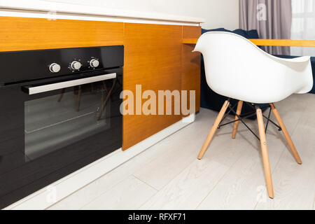 Orange marron moderne en bois dispose d''une cuisine avec armoires et comptoir four noir, tabouret de bar design intérieur et personne ne Banque D'Images