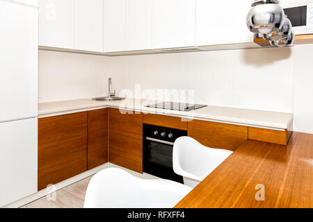 Cuisine moderne en bois blanc orange dispose d'armoires dans petit appartement studio tabouret de bar design intérieur compteur et personne dans la maison minimaliste Banque D'Images