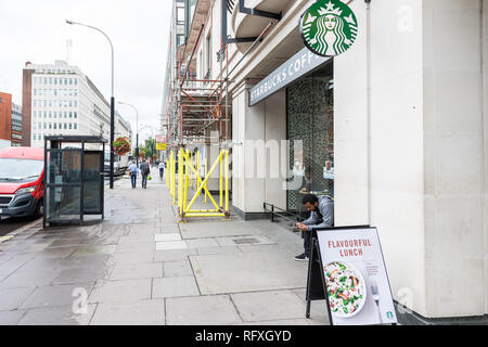 Londres, Royaume-Uni - 12 septembre 2018 : le quartier de Westminster sur la rue Victoria avec des gens assis sur un trottoir par Starbucks Cafe restaurant sign entr Banque D'Images