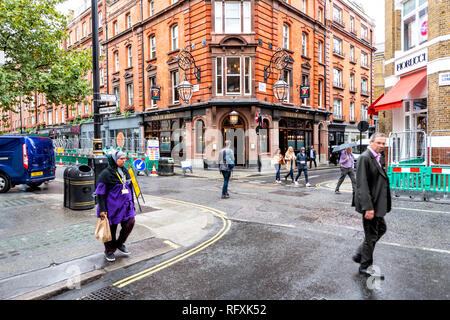 Londres, Royaume-Uni - 12 septembre 2018 : les gens d'affaires et femme homme marchant dans la ville pluvieuse sur trottoir par temps humide Brewer street road shopping à SoHo du Banque D'Images