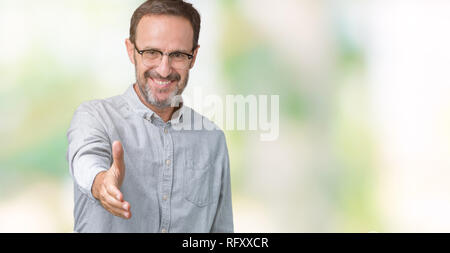 Beau moyen-âge élégant senior man wearing glasses sur fond isolé smiling friendly offrant comme message d'handshake et accueillant. Succès Banque D'Images