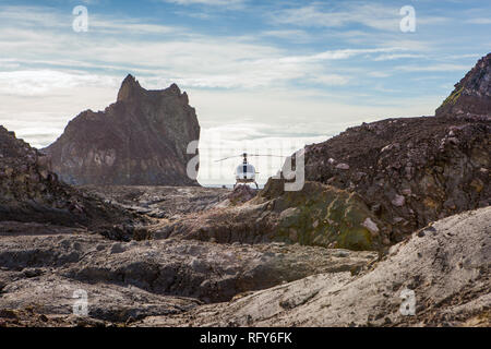 Après l'atterrissage dans le cratère du volcan actif sur Whakaari, White Island, Nouvelle-Zélande, l'hélicoptère se trouve entre les affleurements rocheux. Banque D'Images