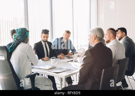 Les dirigeants masculins multiraciale discuter du projet sitting at conference table Banque D'Images