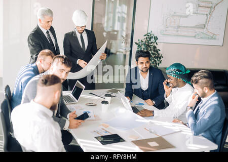 Groupe multiracial des constructeurs et d'architectes de discuter au plan social. Banque D'Images