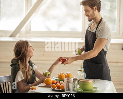 Superbe bel homme est de donner des pommes avec une belle jeune fille enjouée Banque D'Images