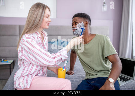 L'homme africain de son visage en face de l'mirrow, dans salle de bains monochrome gris Banque D'Images