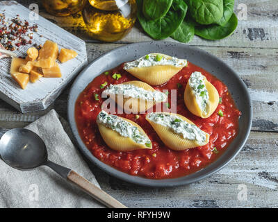 Pâtes cuites conchiglioni farcie épinards et fromage, sauce tomate sur la plaque Banque D'Images